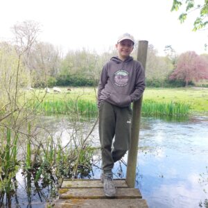 A boy standing next to a pond