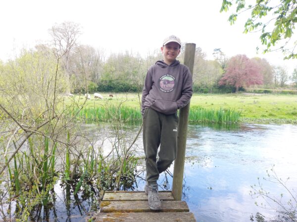 A boy standing next to a pond